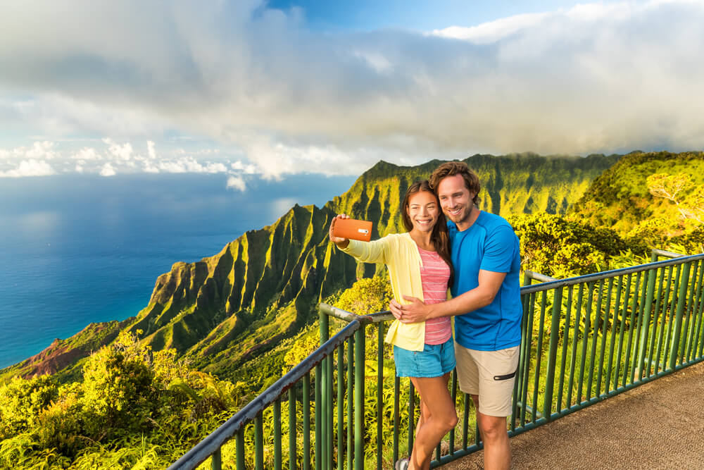 A couple taking a photo at the end of a hiking trail on the Napali coast.